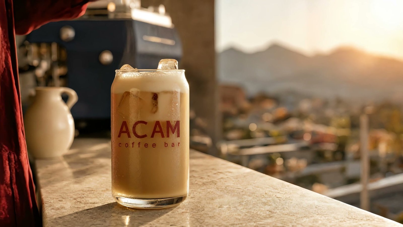 Lata de ACAM llena de café con leche, en reposo sobre la barra al atardecer.