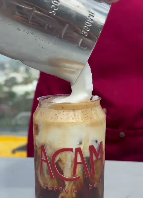 Leche cayendo dentro de una lata de ACAM con la ciudad de Monterrey detrás.